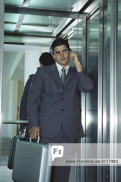 Businessman in elevator using cell phone