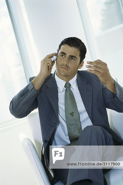 Businessman sitting with legs crossed  using cell phone