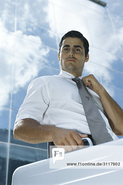 Geschäftsmann vor dem Bürogebäude stehend mit Aktentasche  verstellbarer Krawatte