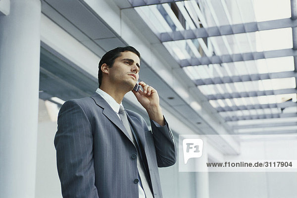 Businessman standing outside office building using cell phone