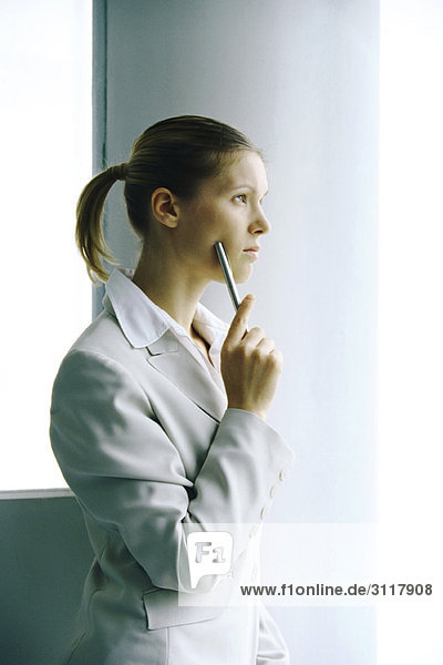 Businesswoman waiting by column  looking away contemplatively