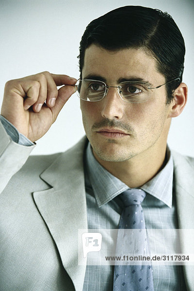 Businessman adjusting glasses  portrait