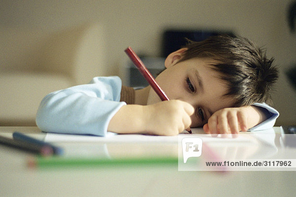Kleiner Junge ruht Kopf auf Arm  Zeichnung mit Buntstiften