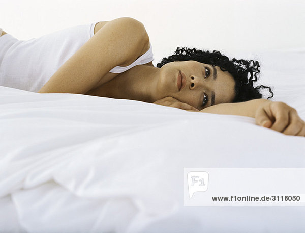 Woman lying on bed daydreaming