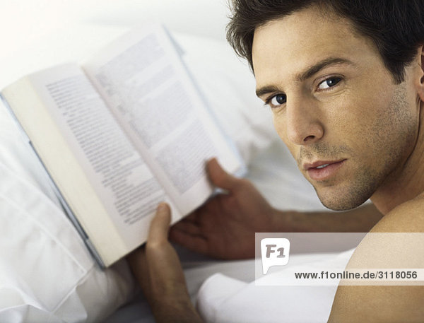 Man holding book  looking over shoulder at camera
