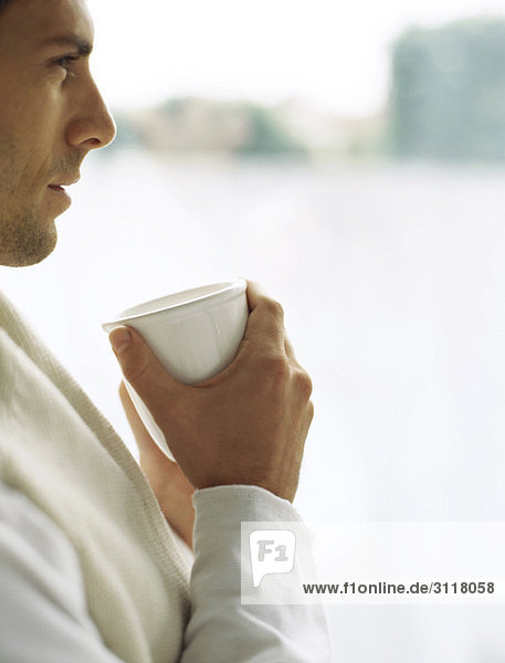Man holding cup of coffee  looking away in thought