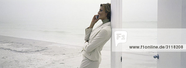 Woman leaning against doorway using cell phone