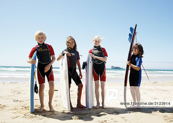 Children standing with surfboards on the beach  front view