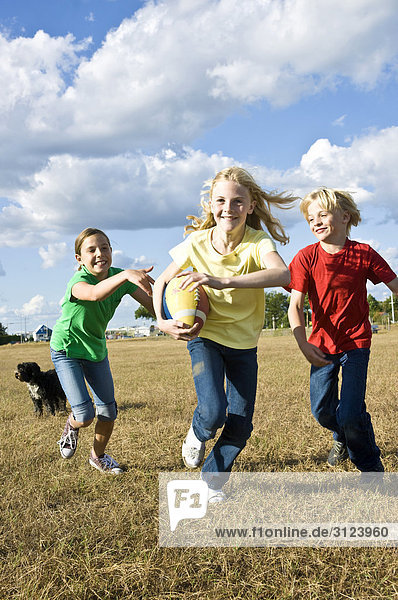 Kinder rennen über ein Feld  Frontal