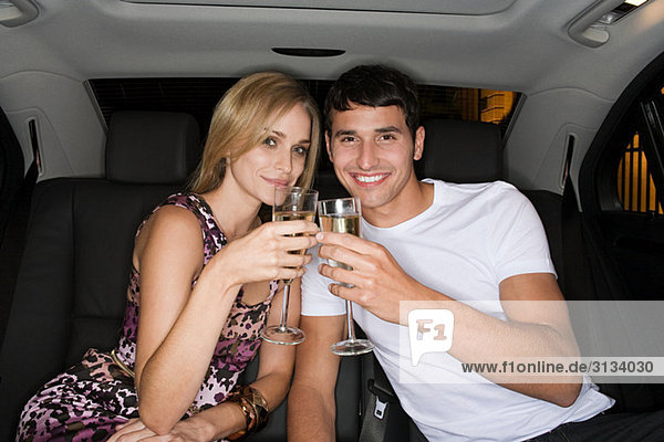 Ein Paar feiert auf dem Rücksitz eines Autos.
