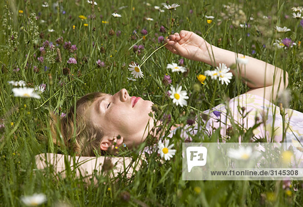 Frau im Gras liegend mit Frühlingsblumen