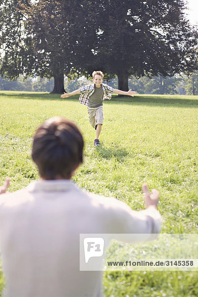 Ein Junge rennt zu seinem Vater in den Park.