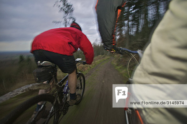 two mountain bikers riding down a track