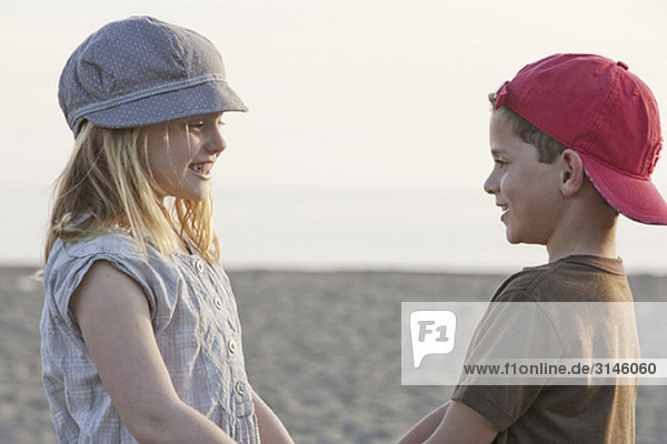 Junge und Mädchen halten Händchen am Strand