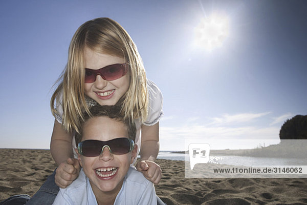 Mädchen und Junge mit Sonnenbrille am Strand