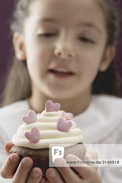 Little girl holding cupcake with sugar hearts