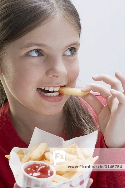 Mädchen ein Pommes Frites-Tüte haltend beim essen