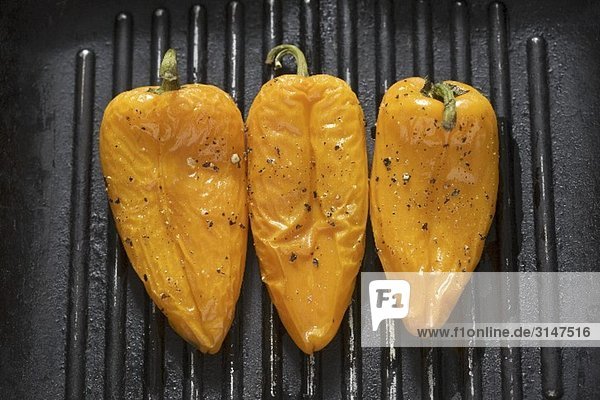 Three yellow peppers in a grill frying pan
