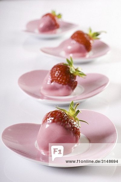 Erdbeeren mit rosa Glasur auf herzförmigen Tellern