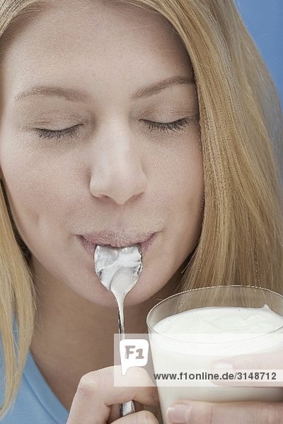 Junge Frau isst Naturjoghurt