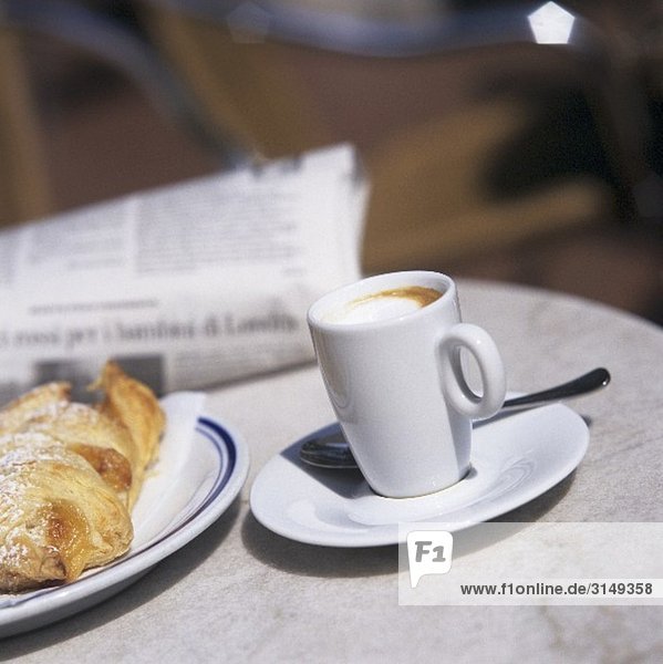 Kaffee Macchiato mit Brioche und Zeitung