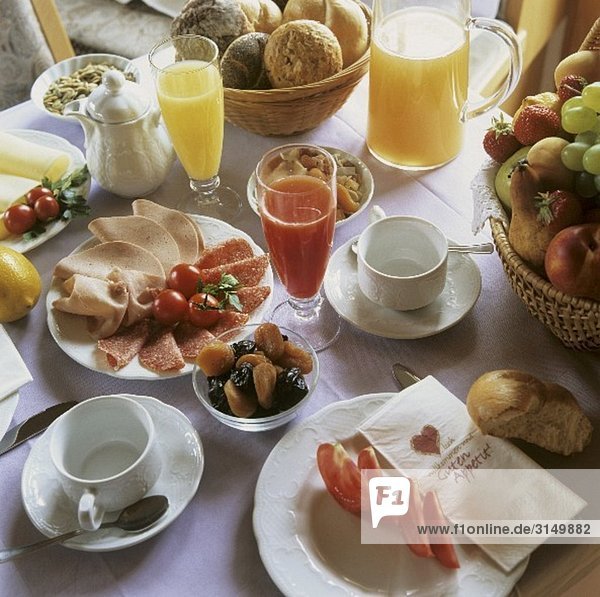 Breakfast table with juices  cold cuts and fruit