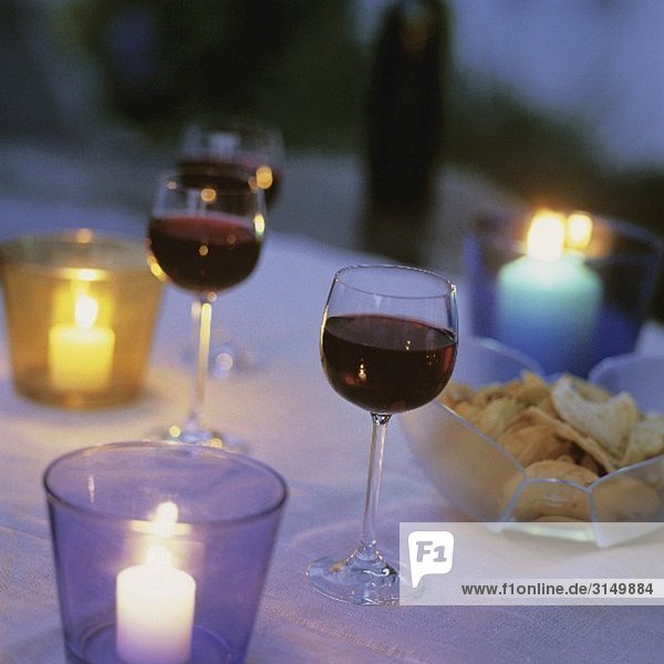 Tisch mit Rotweingläsern & Chips im Kerzenlicht
