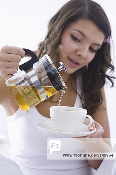 Mädchen giesst Tee in Tasse