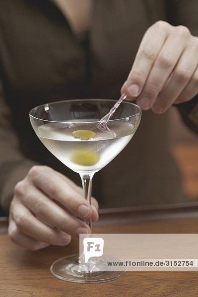 Woman spearing olive in Martini glass