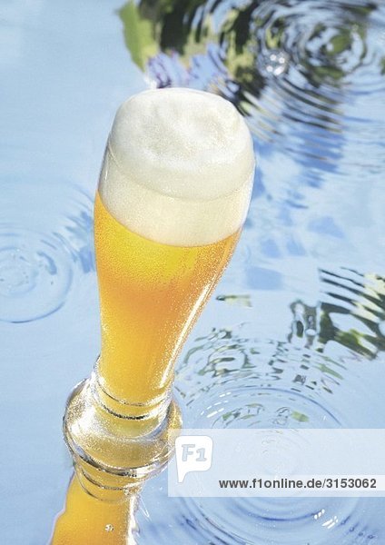 Glas Weissbier auf Wasserfläche