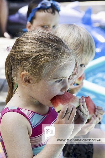 Kinder essen Wassermelone am Pool