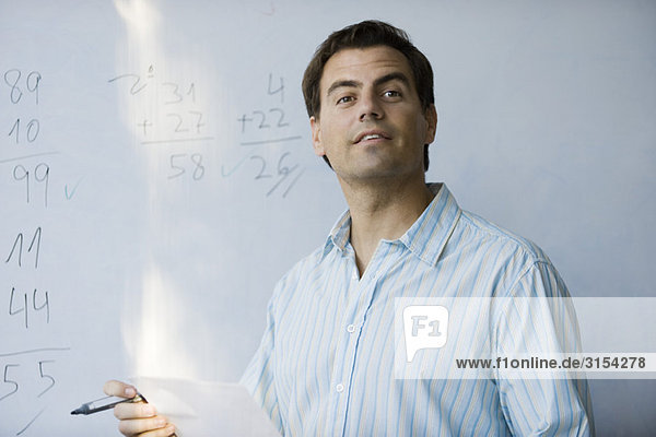 Mathelehrer vor dem Whiteboard erwartungsvoll schauend