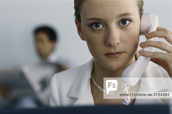 Young businesswoman holding phone to ear  looking at camera