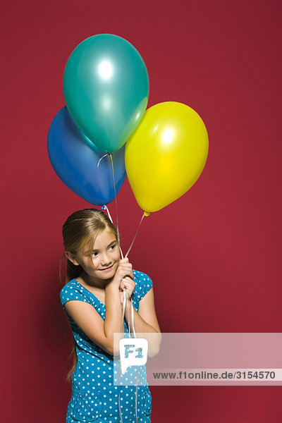 Mädchen hält Luftballons  schaut weg  lächelt