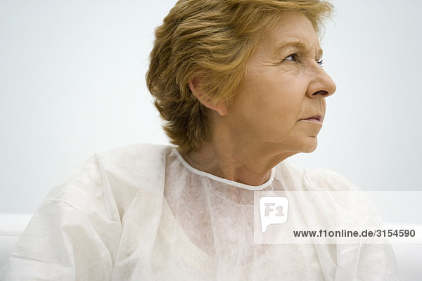 Senior woman wearing examination gown  looking away  portrait