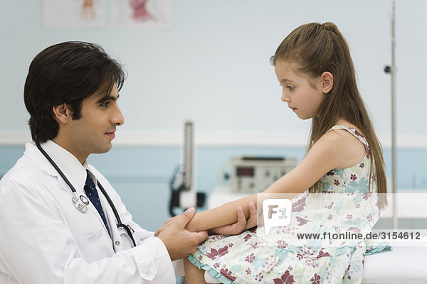 Pediatrician examining little girl's arm