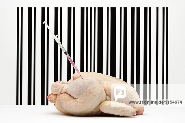 Food-Konzept  rohes Hühnerfleisch mit Spritze im Oberschenkel vor dem Barcode