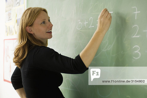 Teacher writing on blackboard