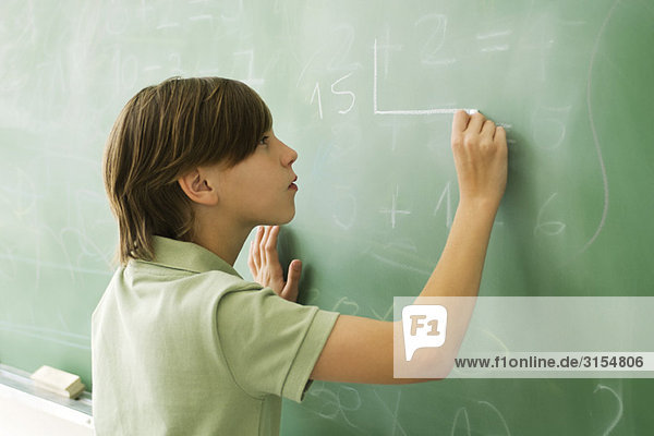 Boy writing on blackboard
