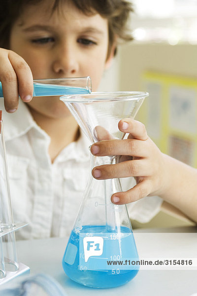 Boy transferring liquid from test tube to beaker using funnel