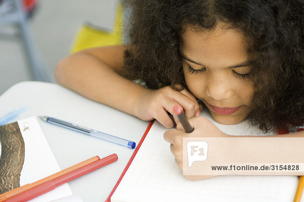 Little girl resting head on desk  drawing on graph paper