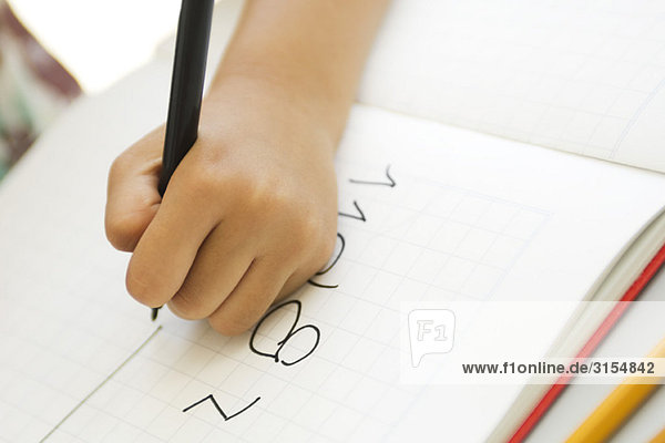 Child's hand writing in notebook