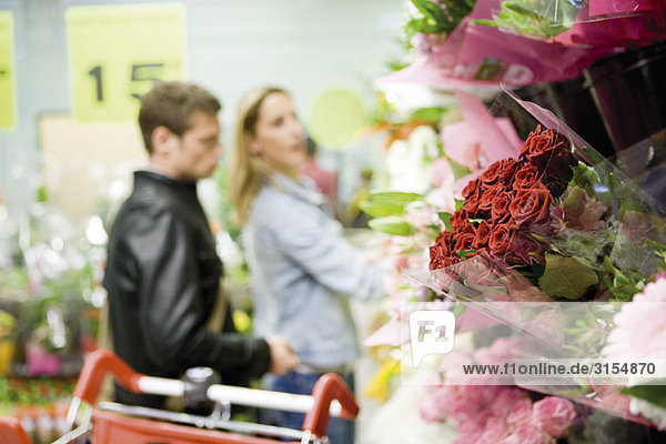 Flower bouquets at flower shop  couples browsing in background