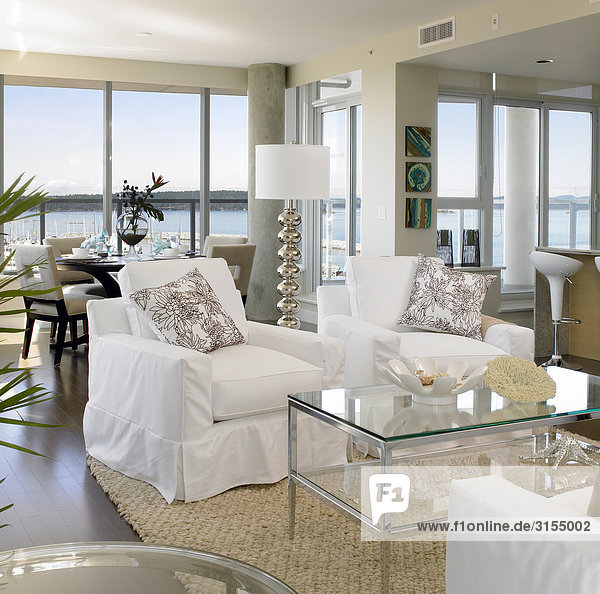 Living room with white furniture and sea view in background
