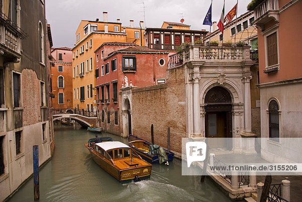Water taxi cruises on narrow canal  Venice  Italy