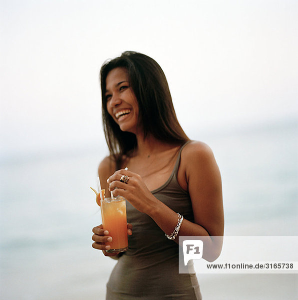 Eine junge Frau mit einem Drink am Strand  Thailand.