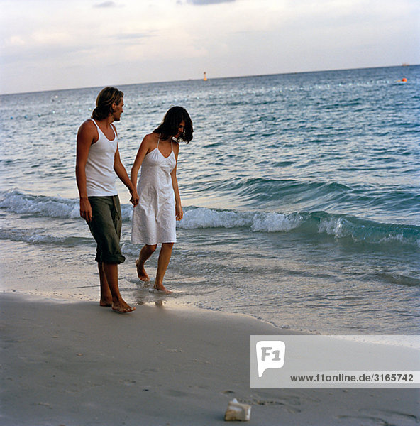 Ein junges paar gehen Hand in Hand am Strand  Thailand.