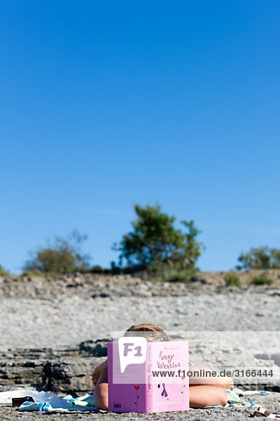 Ein Teenagerin am Strand Schweden lesen.