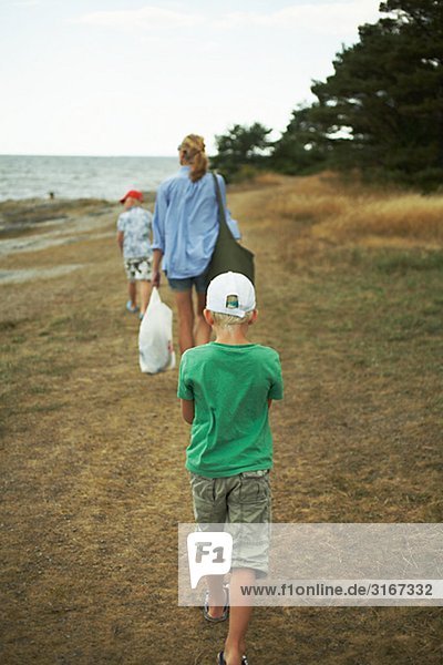Mutter und Söhne zu Fuß auf einem Strand Gotland Schweden.