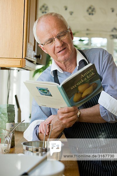 älterer Mann dabei  Kochen  lesen ein Kochbuch  Schweden.